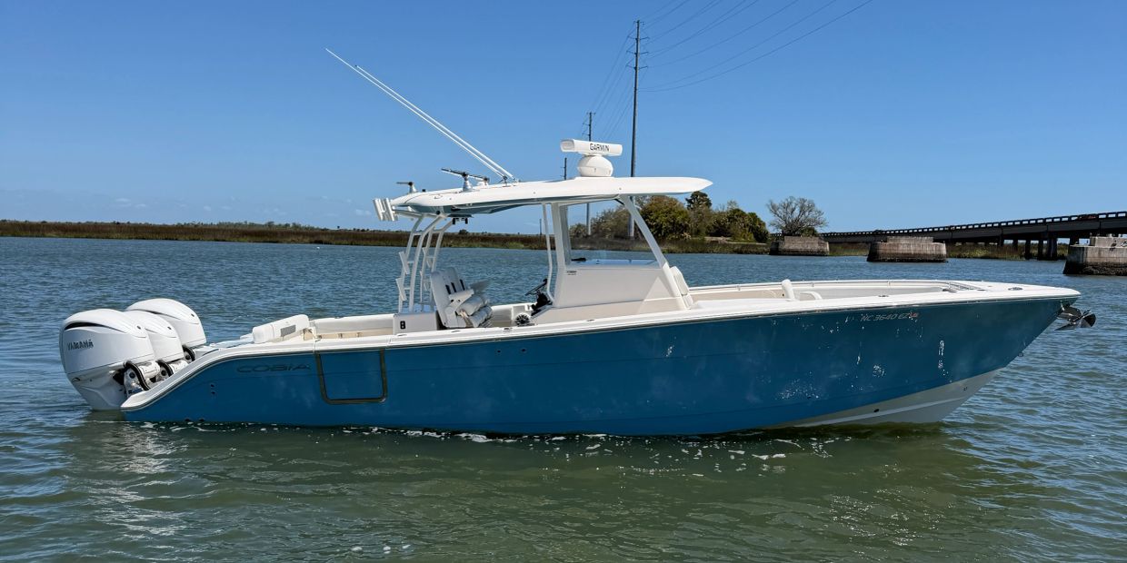 Blue and white fishing boat with twin Yamaha engines on calm water.