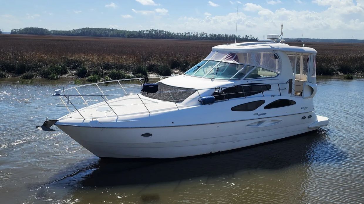 A sleek white yacht docked in calm waters on a sunny day.