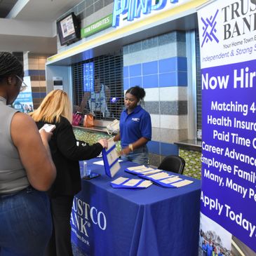 Job fair booth of Trustco Bank with recruiter assisting attendees.