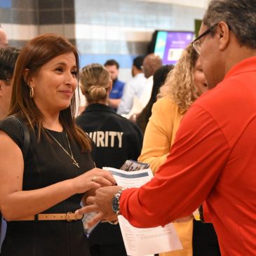 Woman and man exchanging papers at an event.