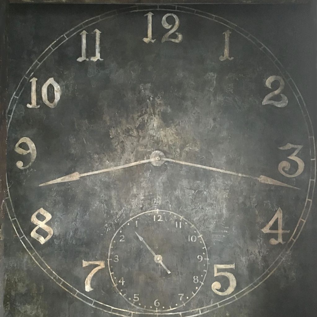Antique-style clock with faded numbers and two sets of hands.