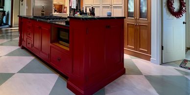 A kitchen featuring a red island with a black countertop and wooden cabinetry.