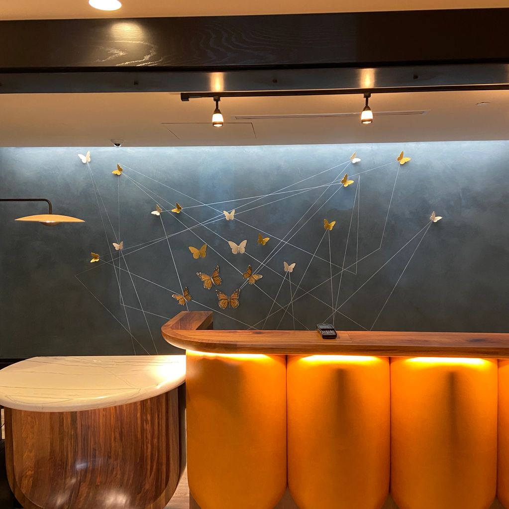 Modern bar counter with yellow lighting and butterfly wall art.