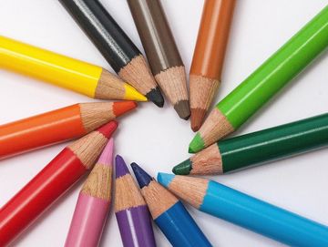 Colored pencils arranged in a circle with sharpened tips pointing toward the center.