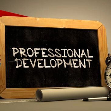Chalkboard with 'Professional Development' text, pen, and rolled paper.