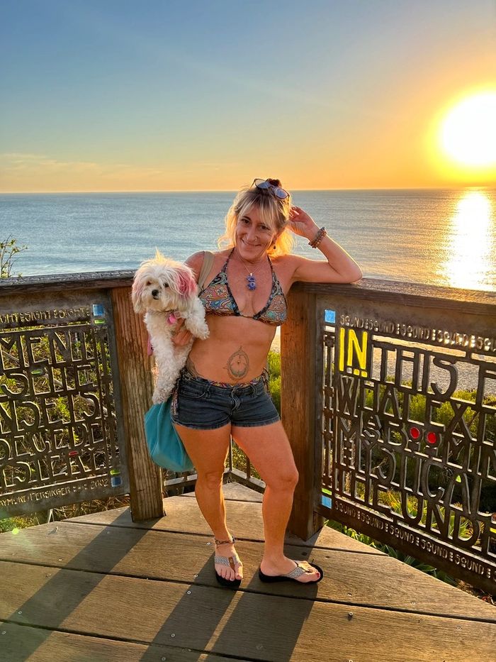 Me standing in front of the Dana Point sunset holding my little dog, Sweet Pea.