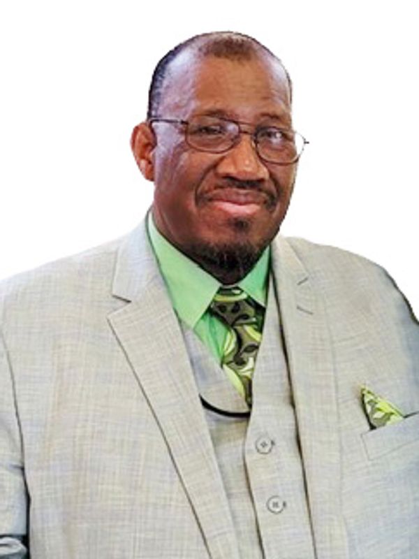 Man in a light gray suit with a green shirt and patterned tie.