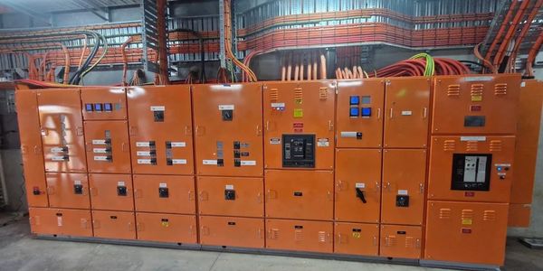 Industrial orange electrical control panels with multiple switches and cables.