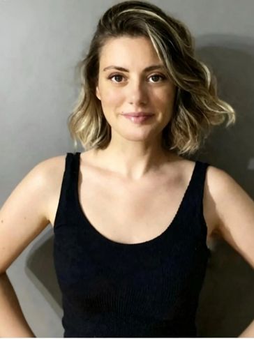 A smiling woman with short blonde hair wearing a black tank top.