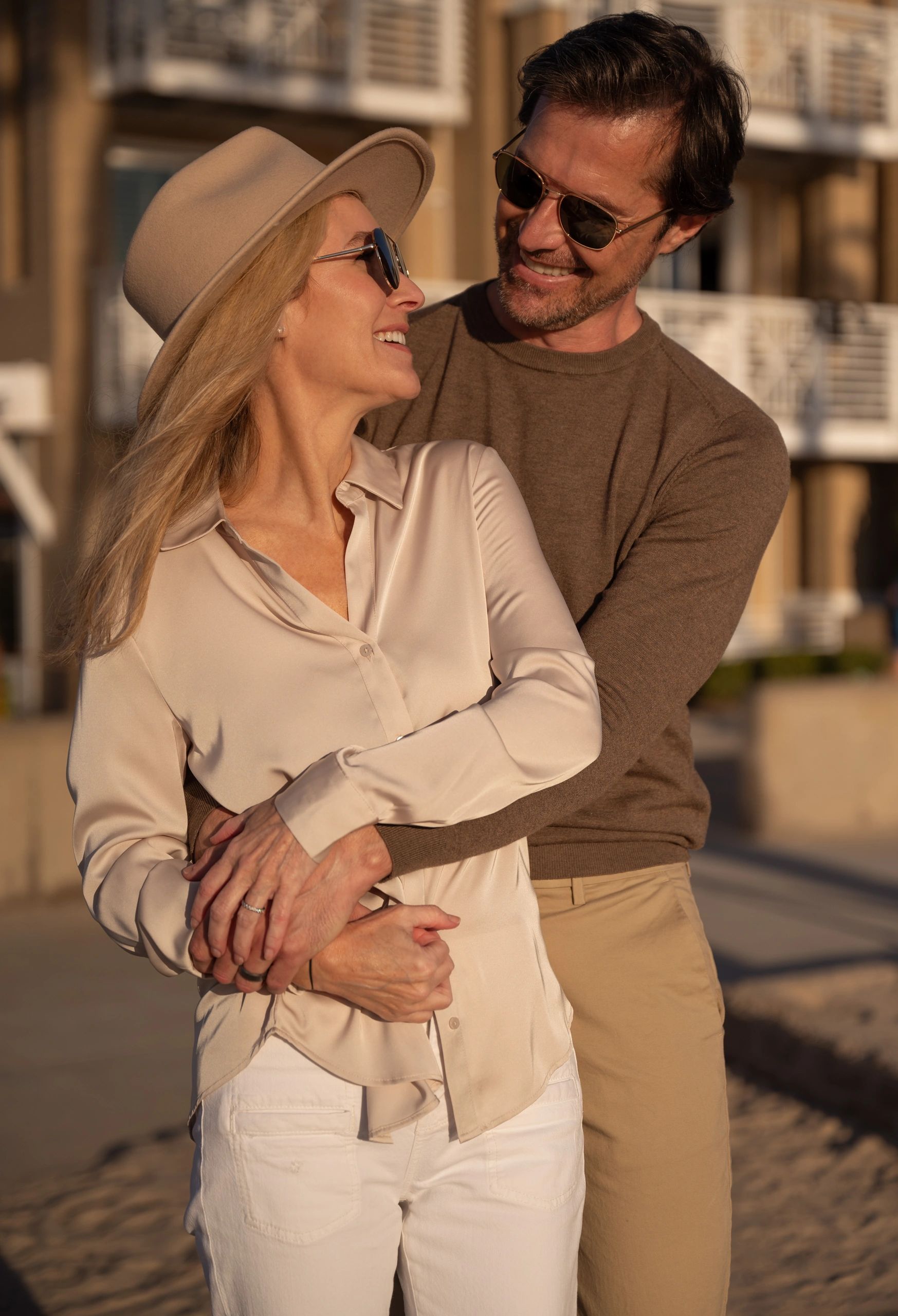 Couple embracing and smiling, enjoying a warm moment outdoors.