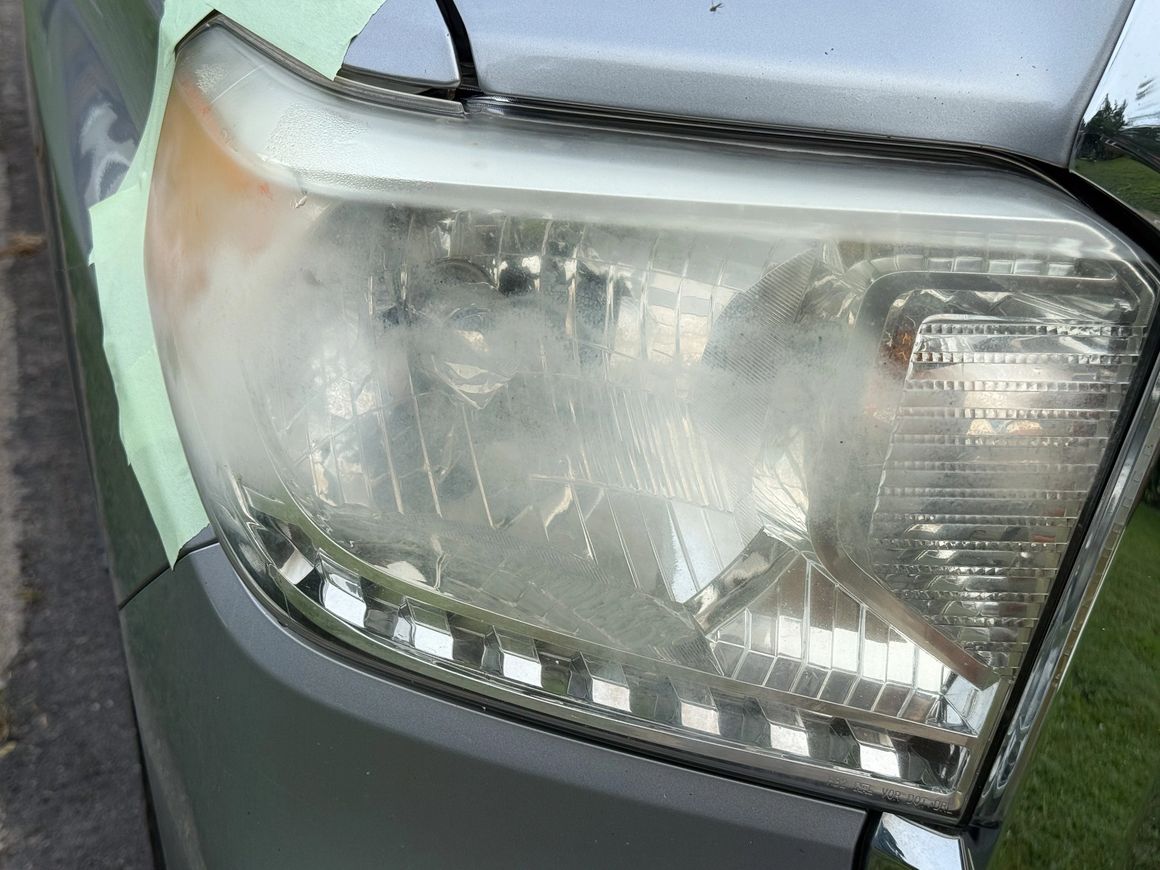 Foggy and oxidized car headlight with masking tape around edges.
