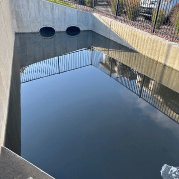 Reflective water surface in a concrete drainage area.