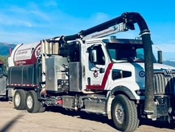 Large industrial vacuum truck under clear sky.