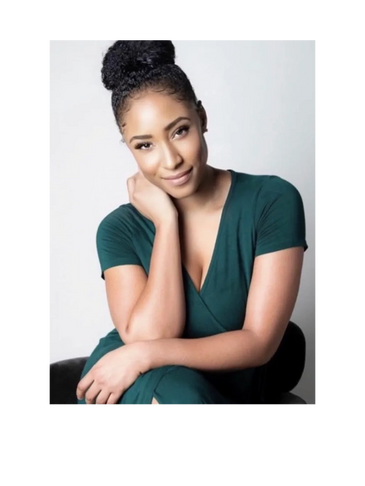Smiling woman with braided bun hairstyle wearing a green dress.