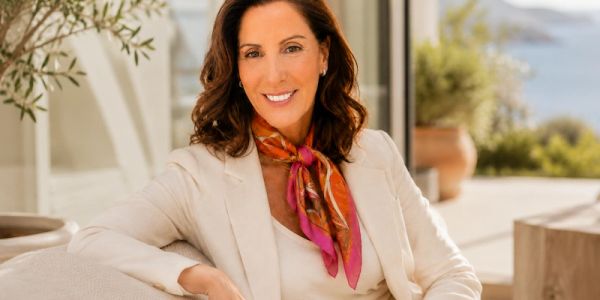 Smiling woman in a white blazer with a colorful scarf.