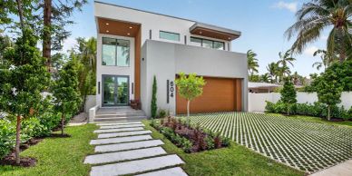 Modern white house with large glass windows and a wooden garage door.