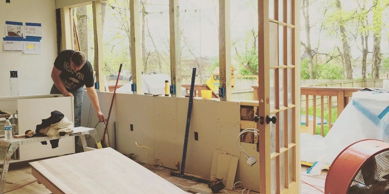 A man working on home renovation with drywall installation and tools around.