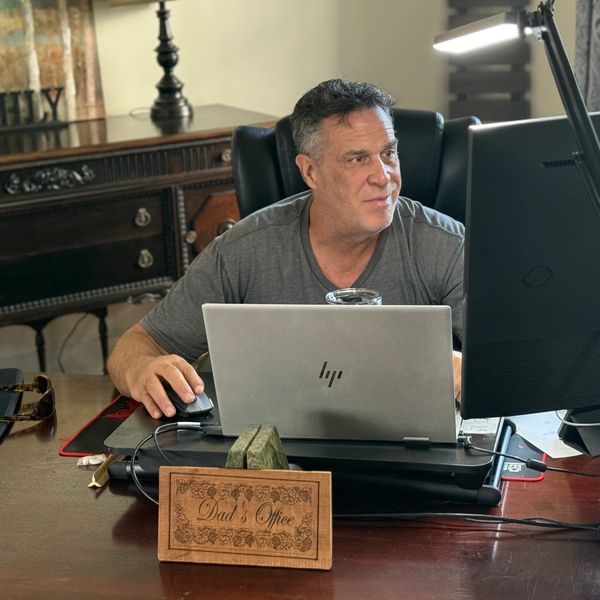 Man working at a desk in a home office labeled "Dad's Office."