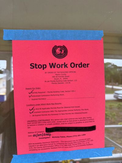 Stop Work Order posted on glass door for unpermitted construction work in Martin County, Florida.