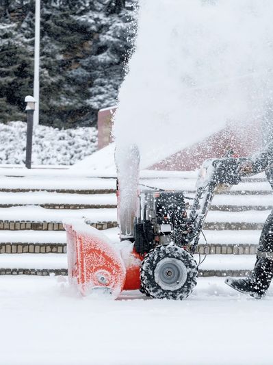 A snow blower clearing snow on steps outdoors.
