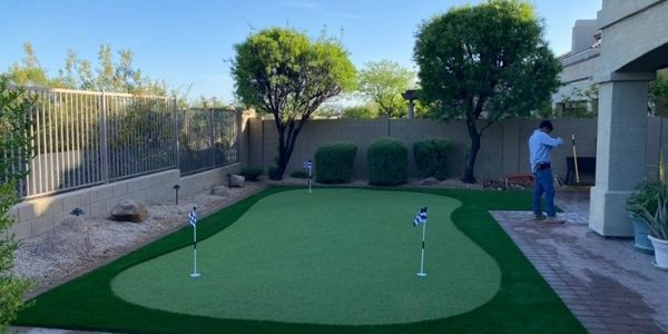 Backyard with a small artificial putting green and person standing nearby.