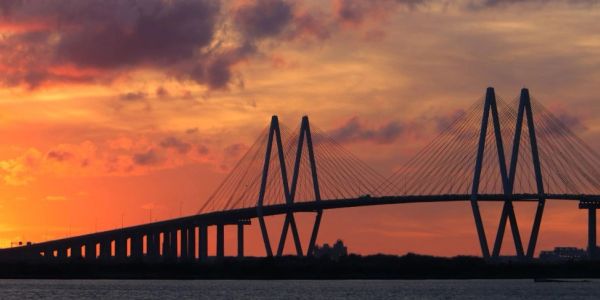 Silhouetted cable-stayed bridge at sunset.
