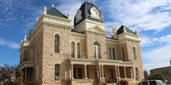 Historic stone courthouse building under blue sky.