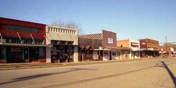 Row of small town storefronts under clear sky.
