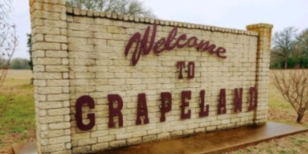 Welcome sign to Grapeland on a brick wall.