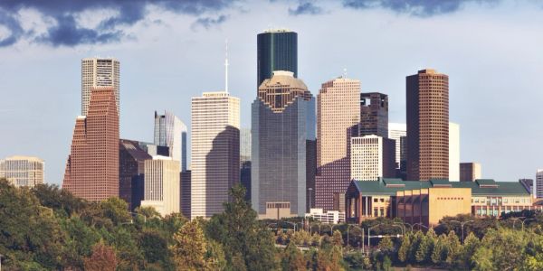 Skyline of a city with tall buildings and greenery.