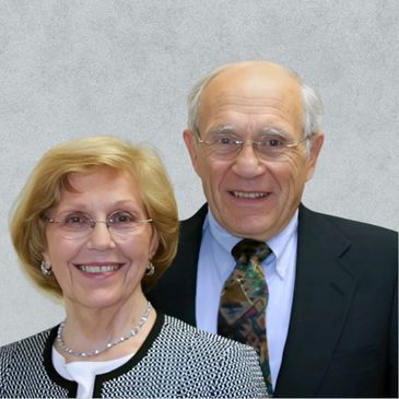 Smiling elderly couple dressed formally, posing together.