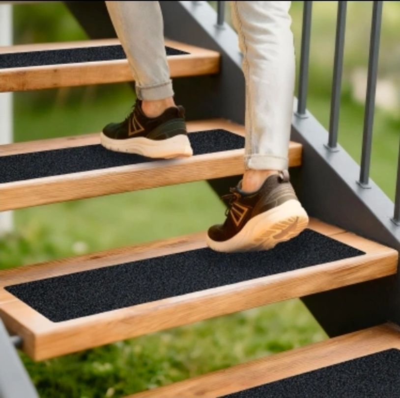 Person walking up wooden stairs with black anti-slip pads.