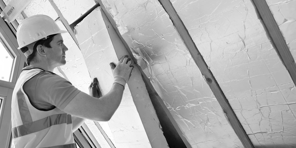 Construction worker installing insulation panels in an attic space.