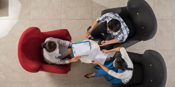 Three people sat on armchairs having a discussion.