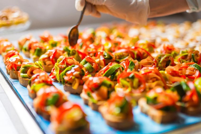 Close-up of colorful vegetable canapés being garnished with a spoon.