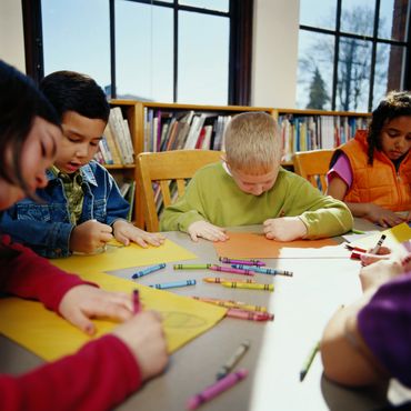 Students drawing and coloring at a table.