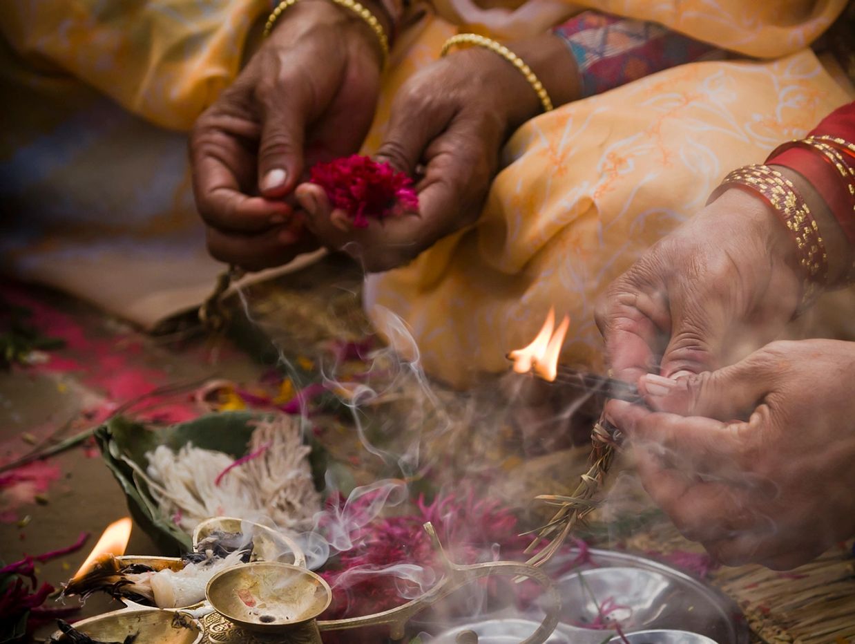 Hands performing a traditional Indian ritual with flowers and fire.