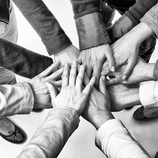 Multiple hands stacked together symbolizing unity and teamwork.