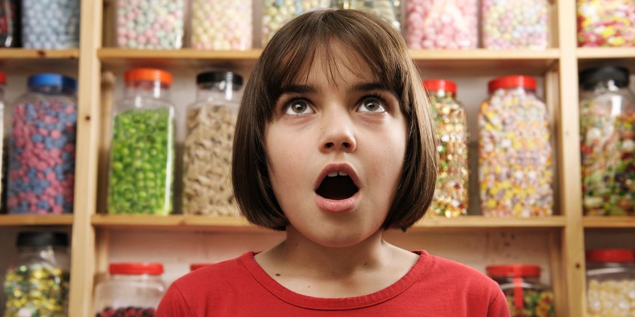 Girl with mouth open having sensory overload in candy shop.