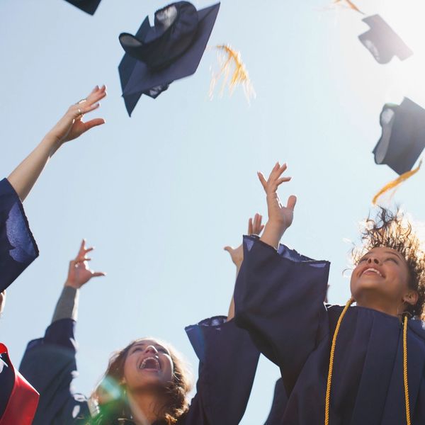 Graduates joyfully toss caps into the air celebrating their achievement.