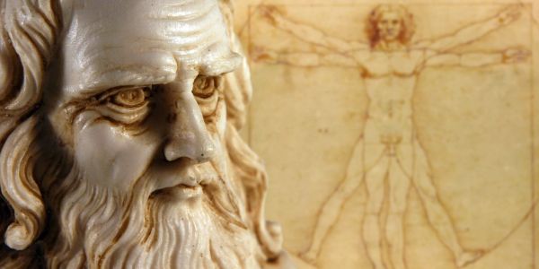 Close-up of a statue with Vitruvian Man drawing in background.