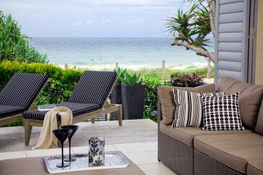 Relaxing beachside patio with lounge chairs and sofa.