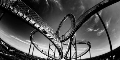 Black and white photo of a looping roller coaster under dramatic sky.