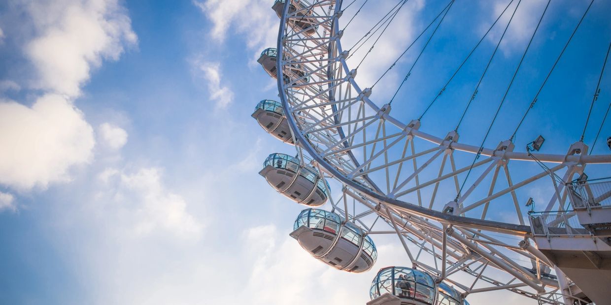 Close-up of a Ferris wheel gondolas against a blue sky with clouds.