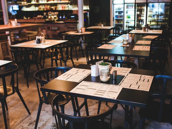 Empty modern restaurant tables set with menus and condiments.