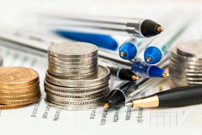 Stacked change beside of stacked pens.