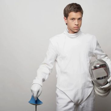 a boy in the fencing dress with helmet in his hand 