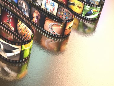 Curled film strips displaying various colorful images on a reflective surface.