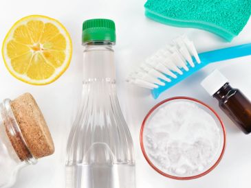 Natural cleaning supplies including lemon, vinegar, baking soda, and a brush.