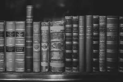 A landscape stock photograph of a shelf full of old books standing together upright.
